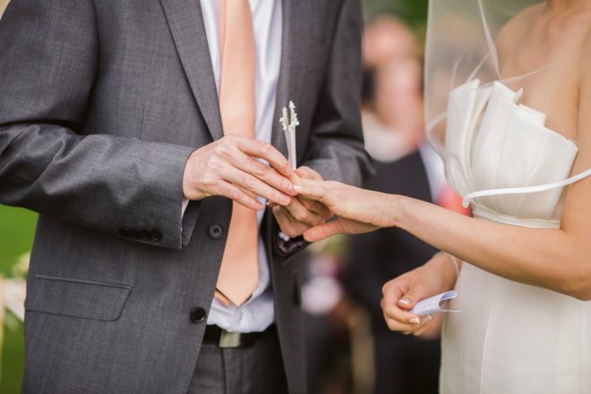 Foto del novio que le pone el anillo de bodas a la novia